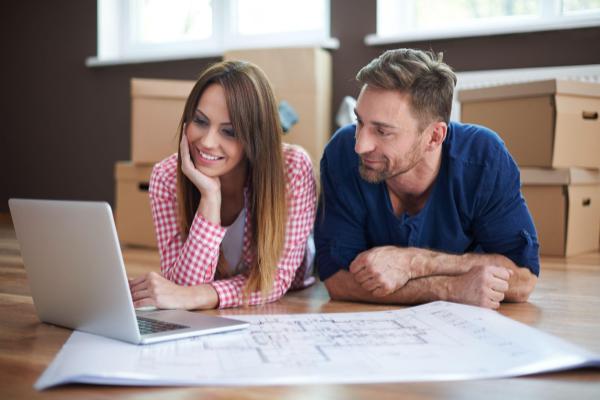 young couple laying on floor and looking at computer