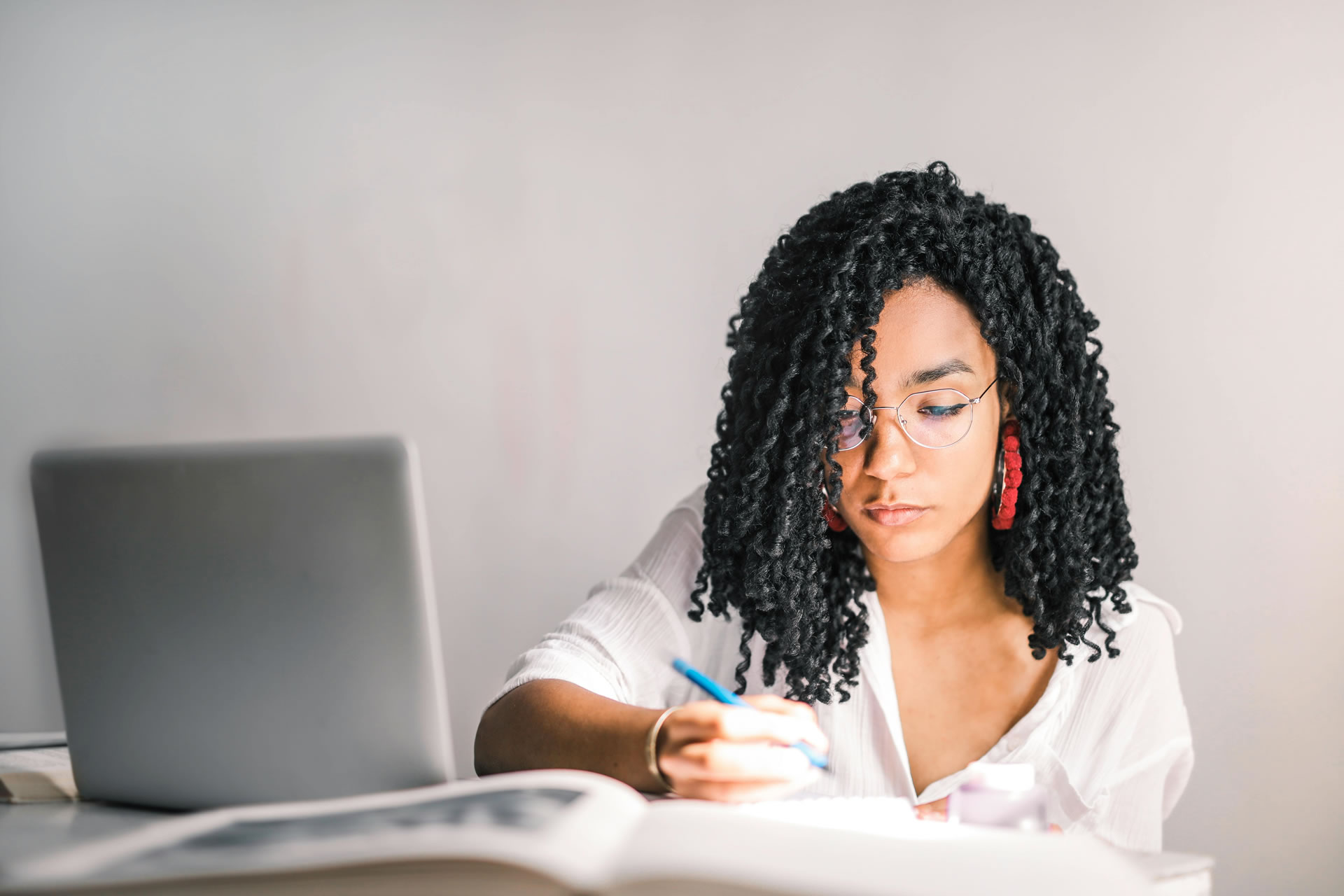 A woman with dreadlocks is seated at a desk, engaged with her laptop, in a bright and organized office environment. A woman with dreadlocks is seated at a desk, engaged with her laptop, in a bright and organized office environment.