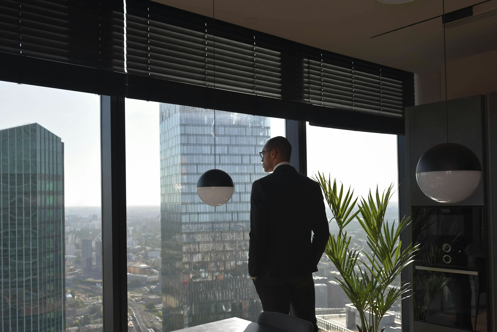 A professional standing confidently on a rooftop overlooking a city skyline at sunrise, symbolizing achievement and continuous improvement.