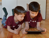 two boys looking at a tablet two boys looking at a tablet