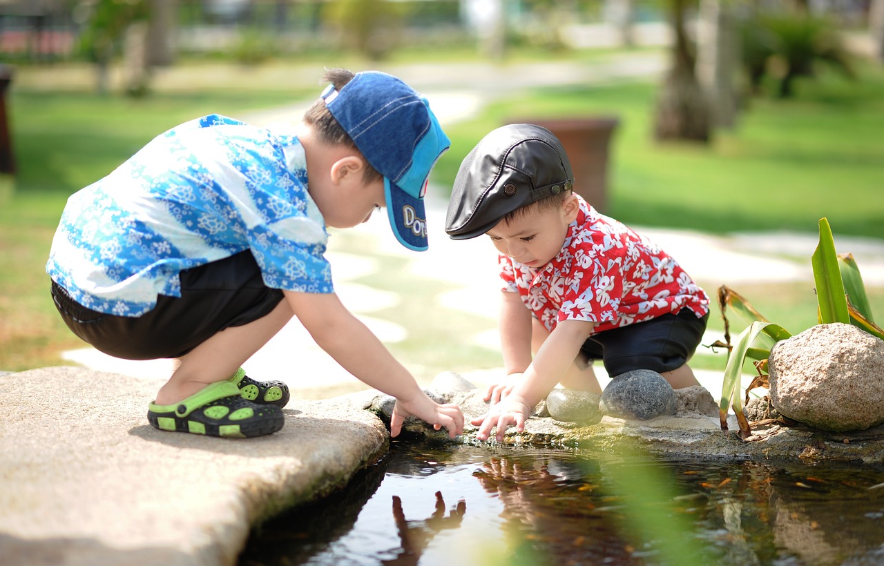 two boys exploring the edge of a pond two boys exploring the edge of a pond
