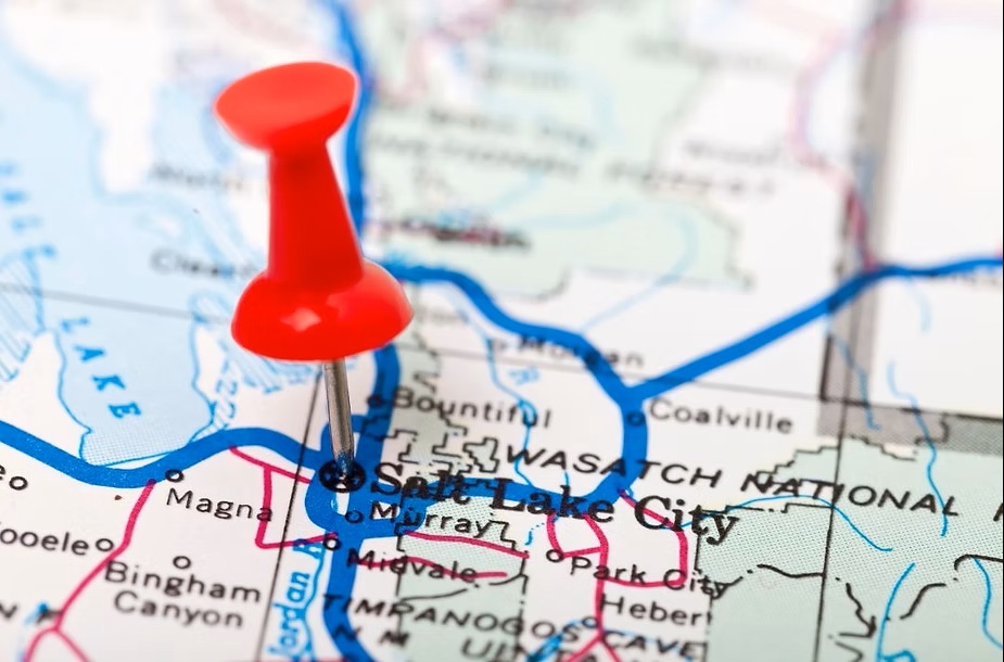 A close-up of a red pushpin marking the location of Salt Lake City on a road map of Utah.
