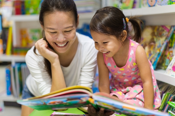 Childcare teacher reading to a smiling toddler - Impact of Childcare on Early Language Development