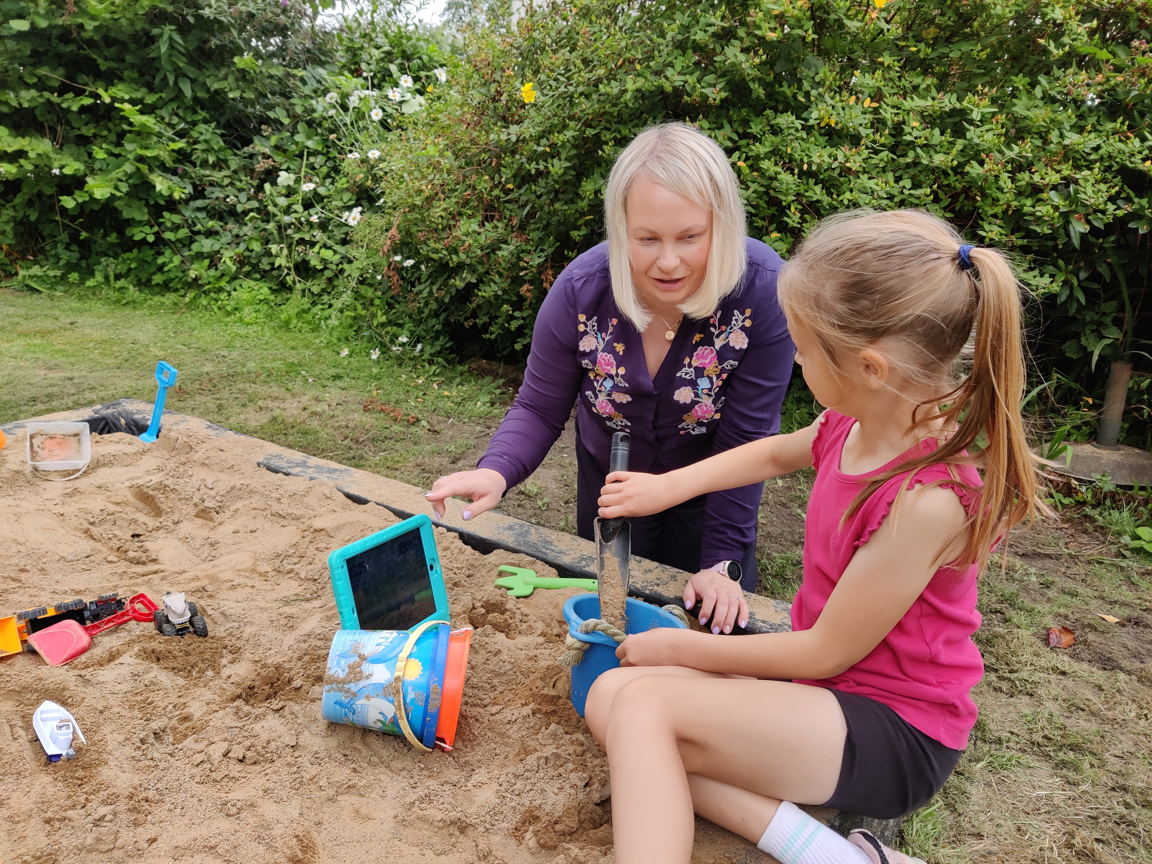 Speech therapist modelling a communication device in sandpit Speech therapist modelling a communication device in sandpit