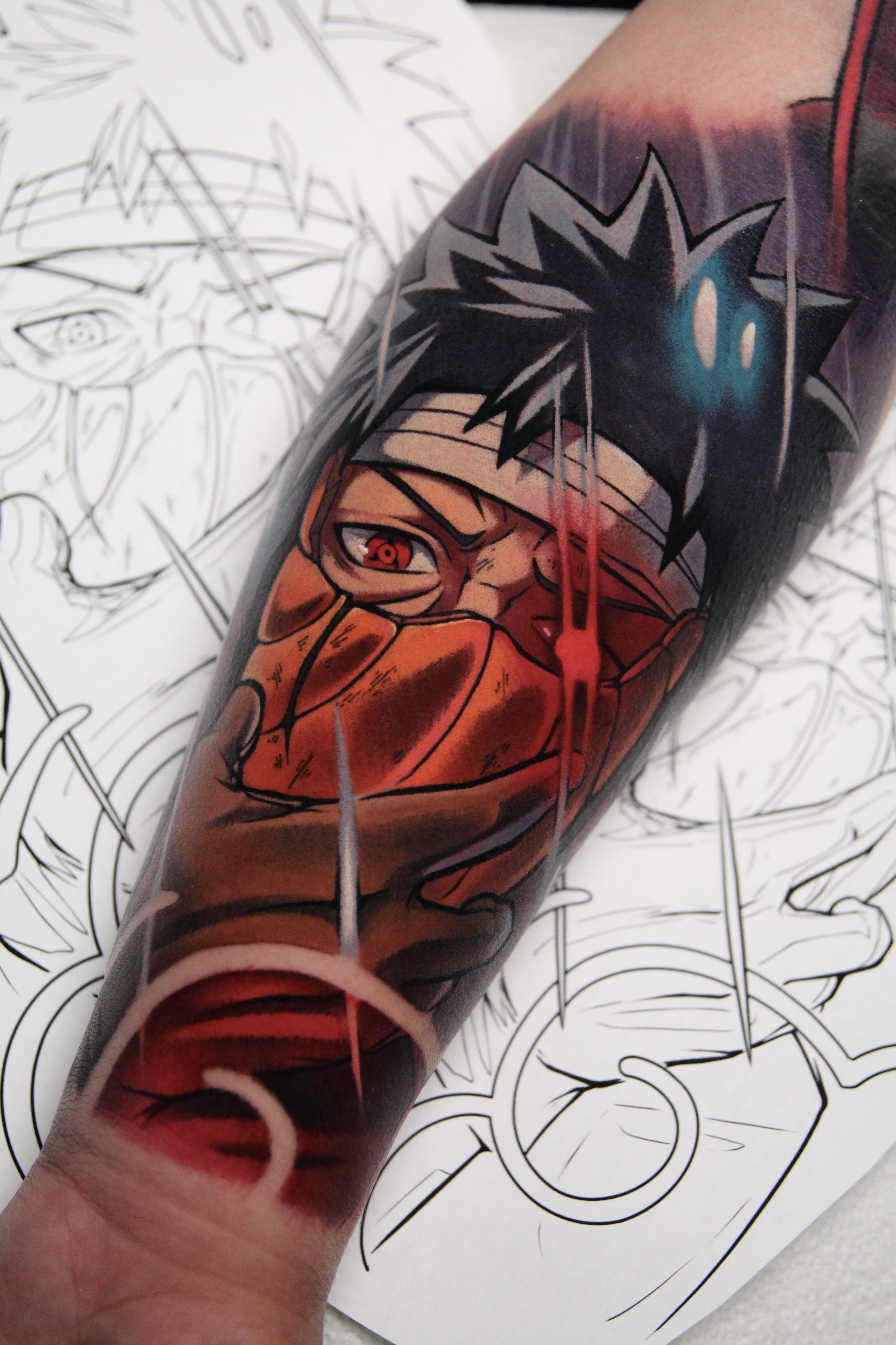 A detailed Naruto tattoo of Obito Uchiha wearing his broken mask, featuring bold shading, intricate colorwork, and intense contrast that captures his tragic reveal beautifully—perfect for anime tattoo enthusiasts seeking a powerful, symbolic design. A detailed Naruto tattoo of Obito Uchiha wearing his broken mask, featuring bold shading, intricate colorwork, and intense contrast that captures his tragic reveal beautifully—perfect for anime tattoo enthusiasts seeking a powerful, symbolic design.