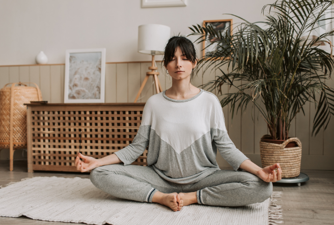Person meditating in a contemporary apartment with soft holographic ancient patterns floating around