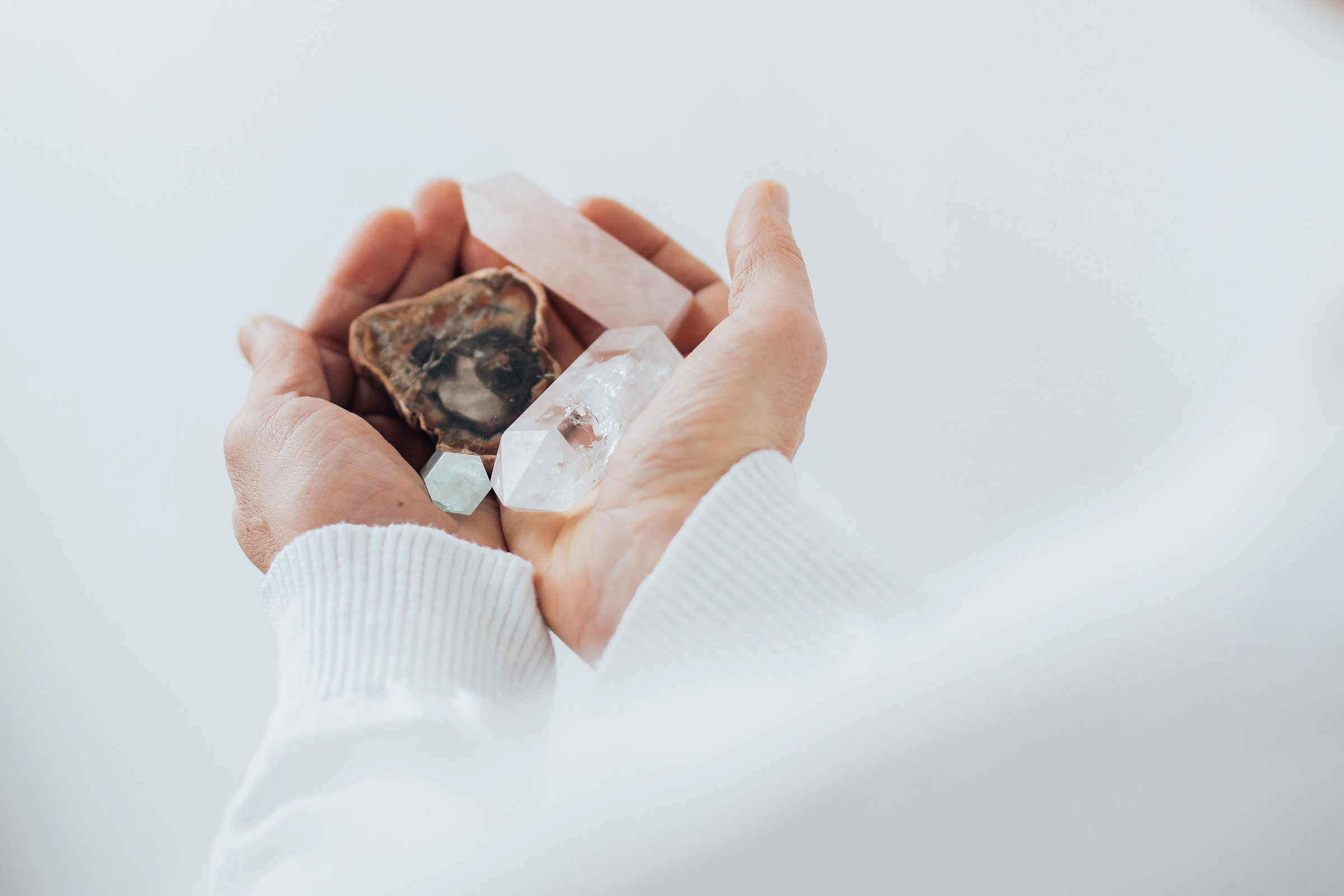 Hands holding a variety of crystals, ready for cleansing and charging.