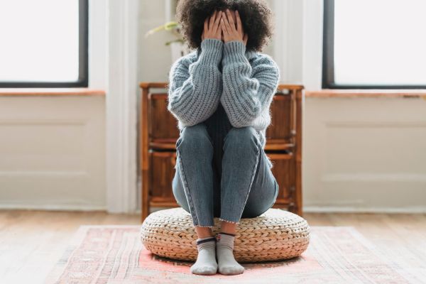 Woman sitting on a pillow holding her face in her hands