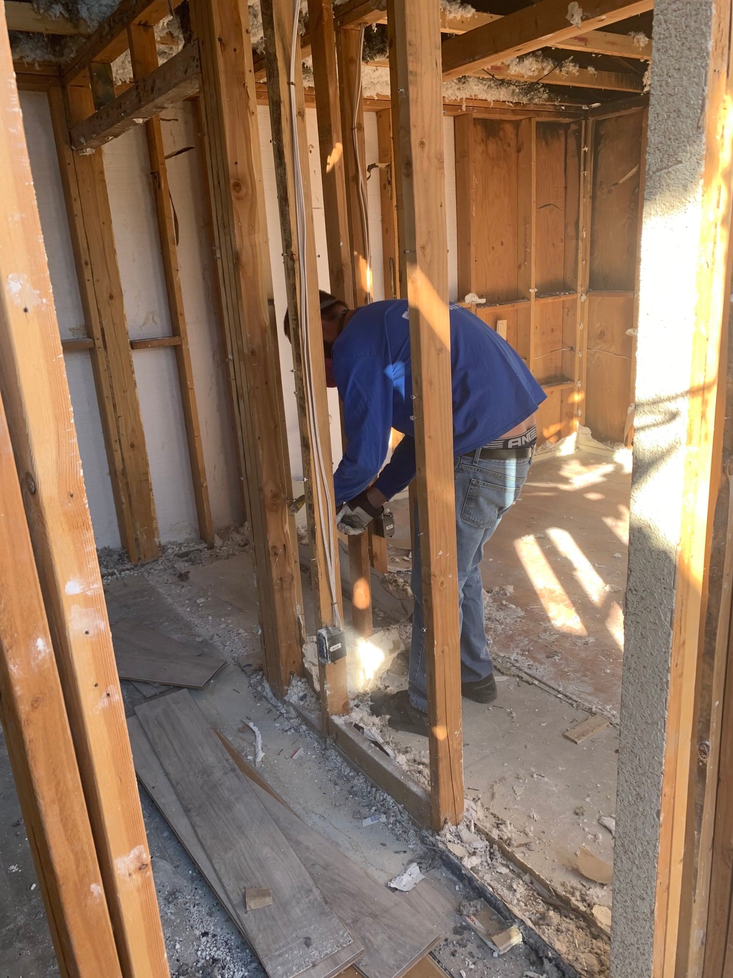 a person in a blue shirt working in a room with wood framing