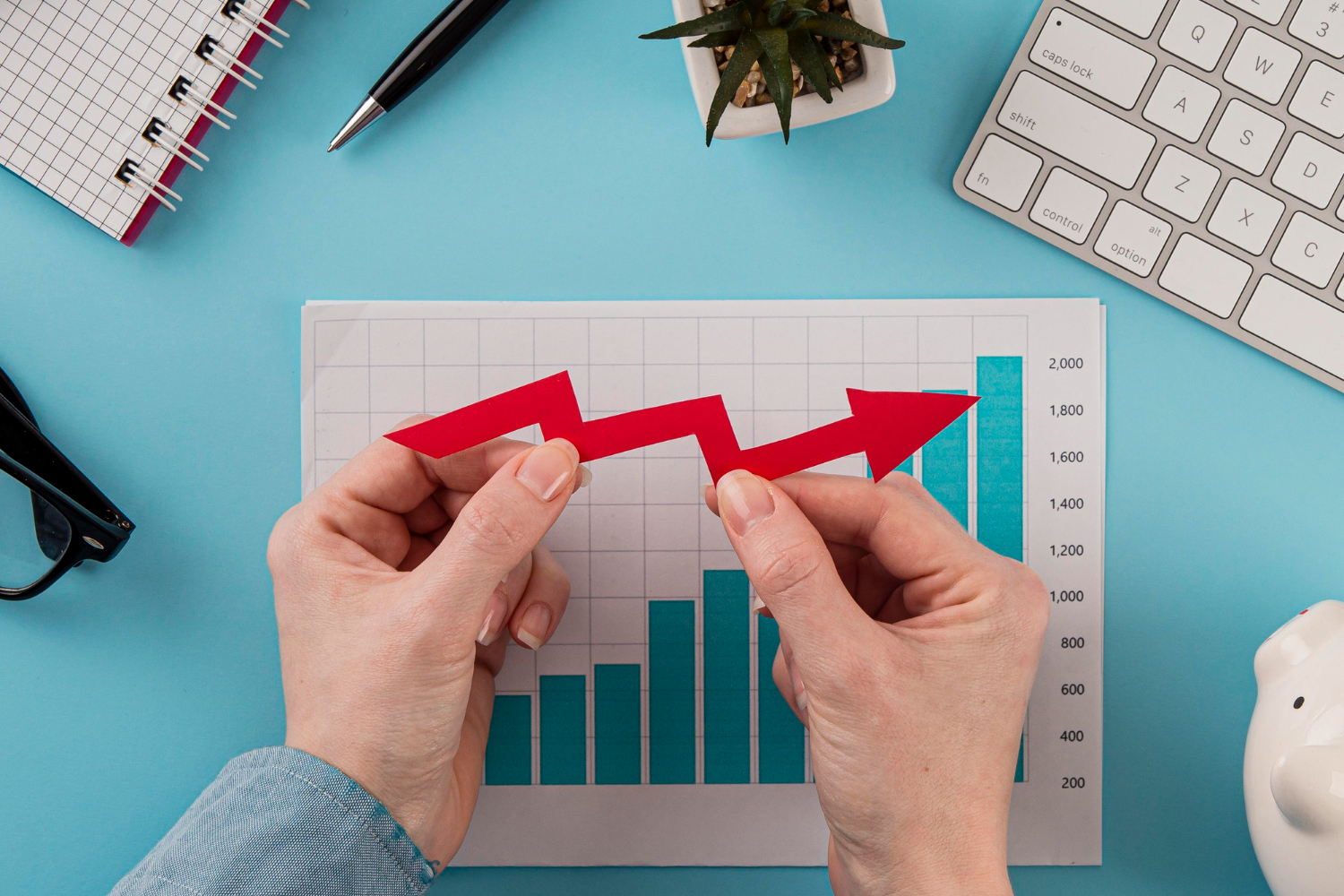 Top view of business items with growth chart and hands holding arrow Top view of business items with growth chart and hands holding arrow