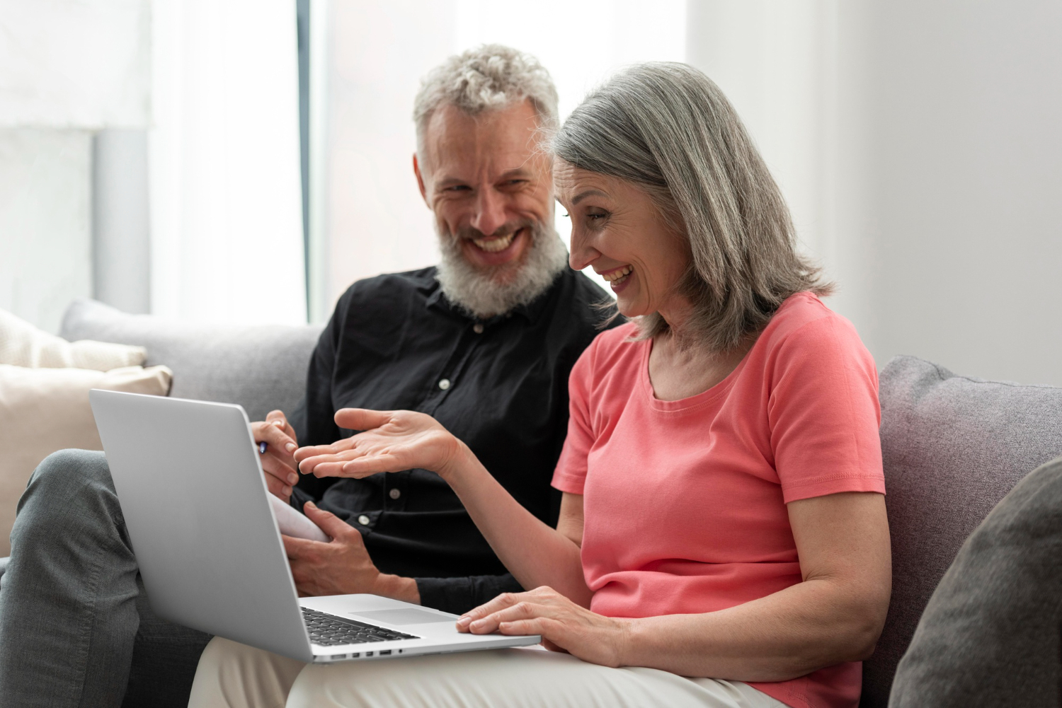 Mature couple sitting on a couch with a laptop, pen and paper. Very happy. Mature couple sitting on a couch with a laptop, pen and paper. Very happy.