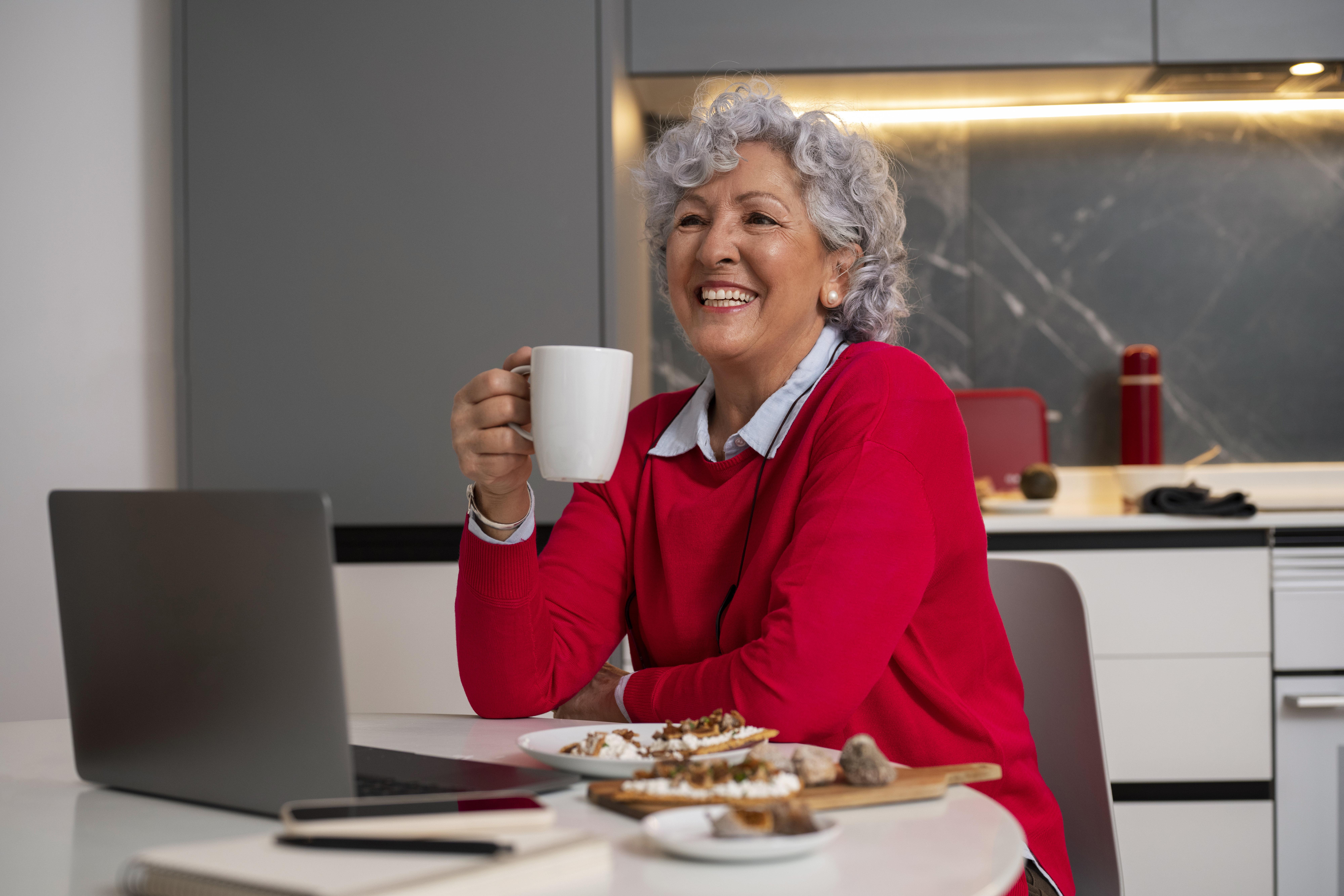Senior woman eating figs dish at home and using laptop Senior woman eating figs dish at home and using laptop