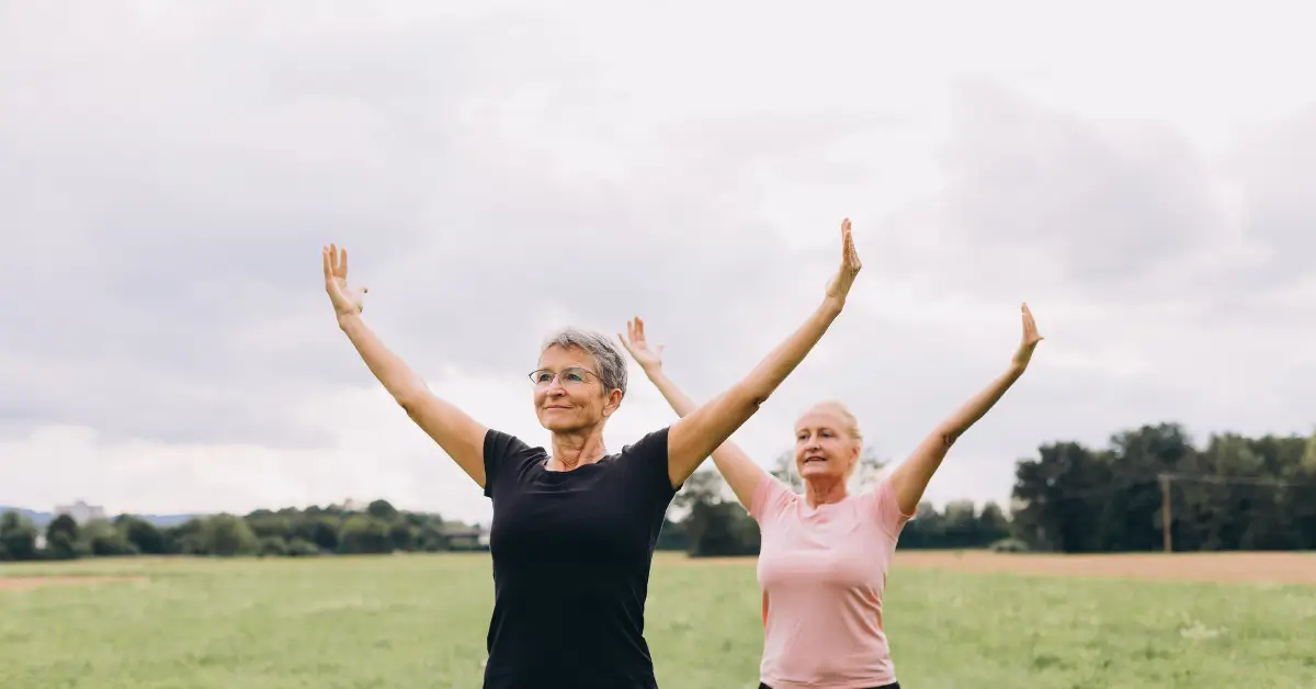 Two older women practicing yoga outdoors, showcasing how physical activity can boost energy and combat fatigue after menopause. Two older women practicing yoga outdoors, showcasing how physical activity can boost energy and combat fatigue after menopause.