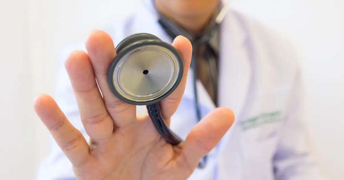 A doctor in a white coat holds a stethoscope towards the camera, with the chest piece in focus. A doctor in a white coat holds a stethoscope towards the camera, with the chest piece in focus.