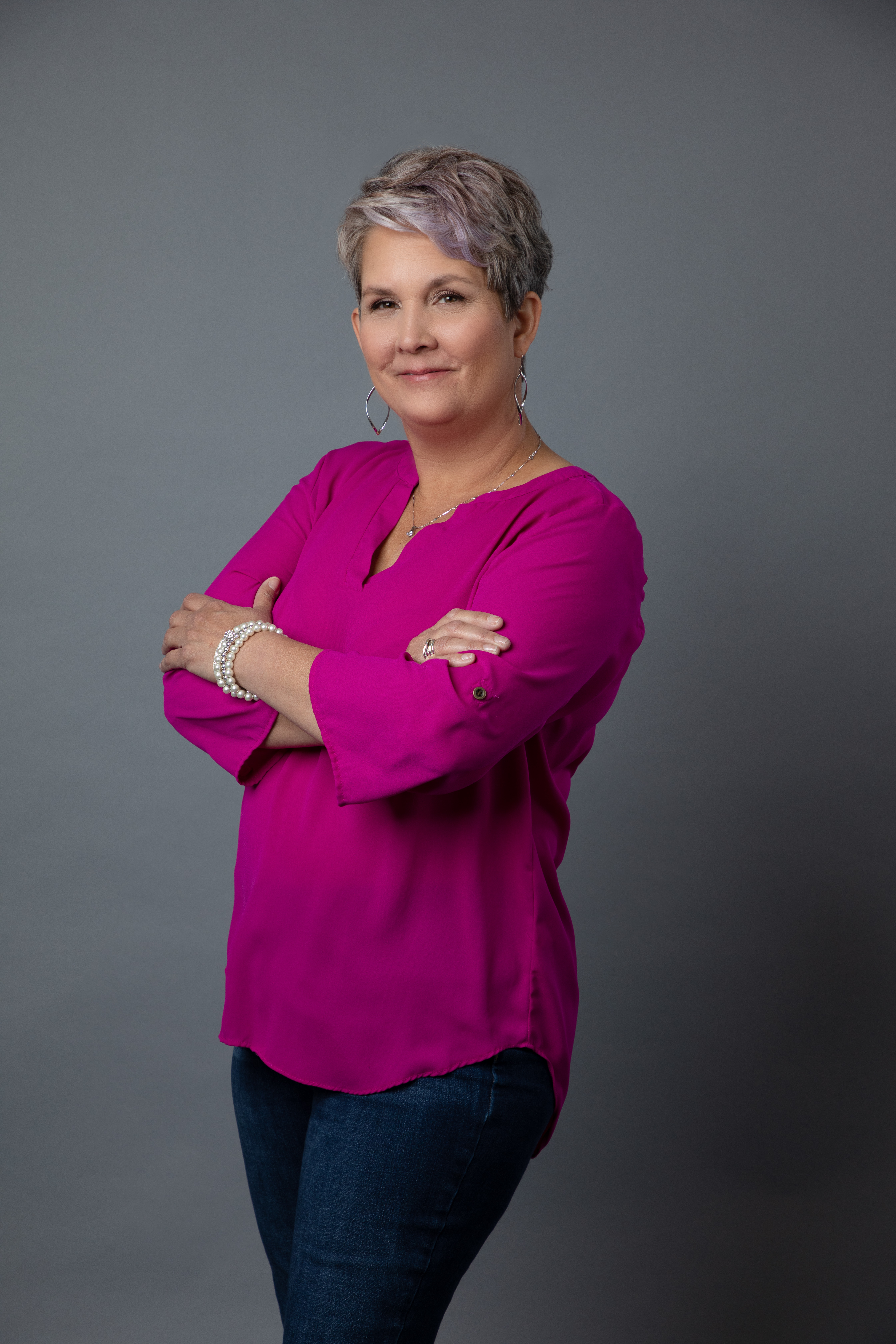 Headshot of a woman with short grey hair in a hot pink top