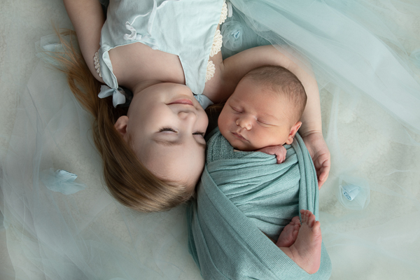 Big sister Rowan cradles baby brother Lennox with the tulle of her skirt as the backdrop