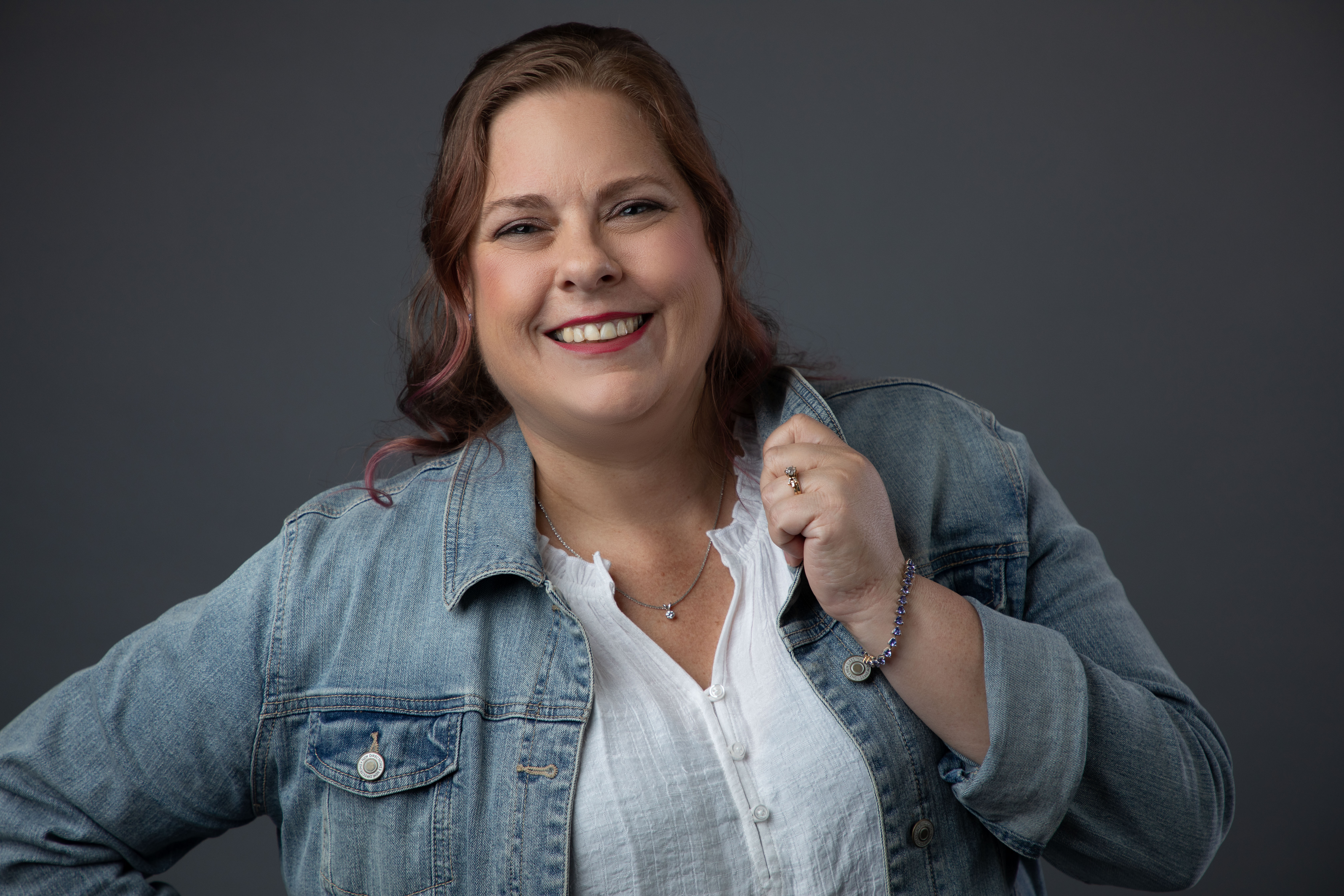 Headshot of a woman in a jean jacket and white top