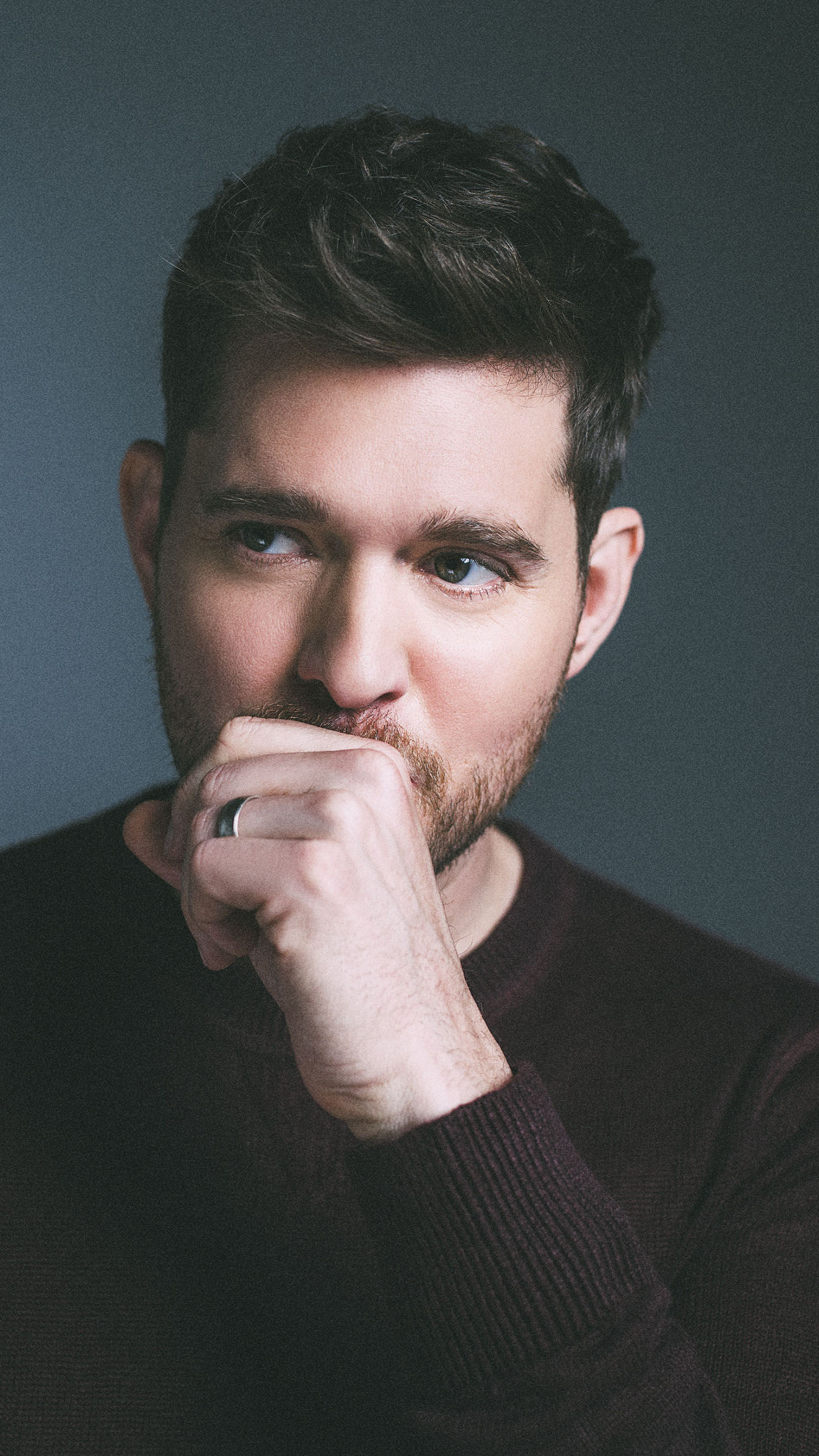 Close-up portrait of a thoughtful Michael Bublé with short dark hair and a trimmed beard, wearing a dark sweater and resting his hand against his face in a contemplative pose. Close-up portrait of a thoughtful Michael Bublé with short dark hair and a trimmed beard, wearing a dark sweater and resting his hand against his face in a contemplative pose.