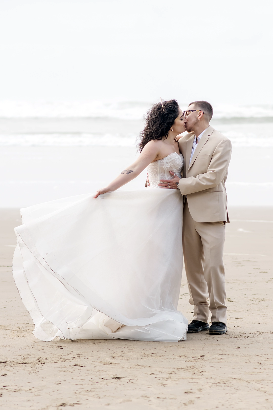 Couple on a beach. Bride swings her dress back and forth while looking at the groom. Couple on a beach. Bride swings her dress back and forth while looking at the groom.