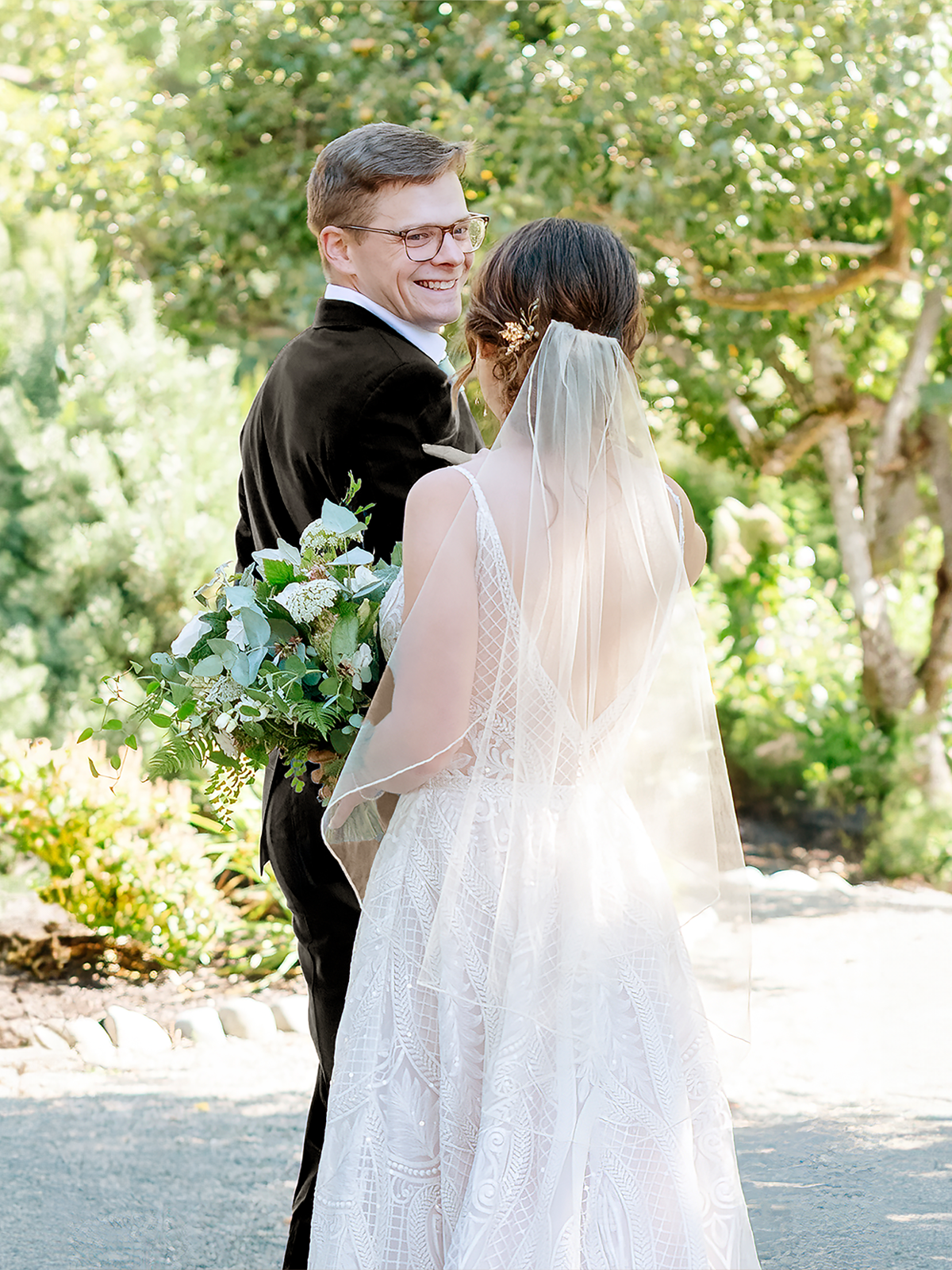 A refined couple in elegant attire, the bride with a bouquet of white and blue flowers and the groom in a classic suit, shares a heartfelt moment highlighting the sophisticated allure of a Seattle wedding photographer's wedding portraiture.