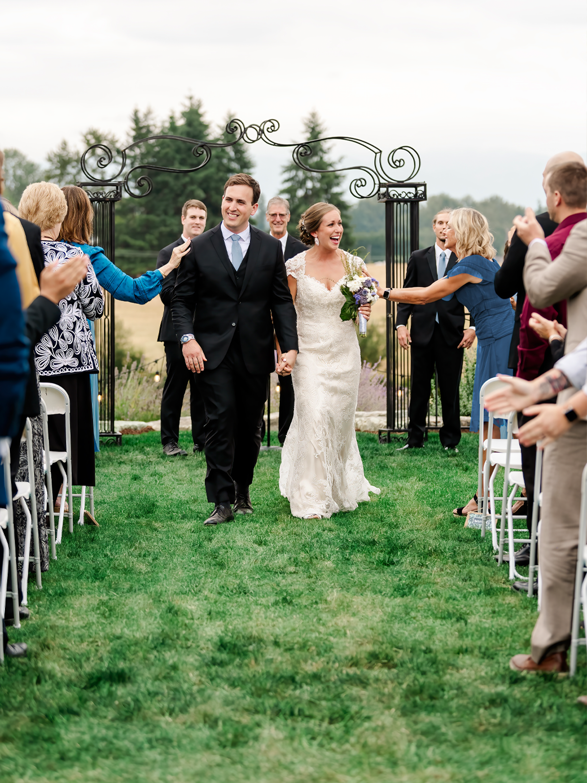 A modern-classic couple shares a joyful moment, the bride in a flowing dress with a vibrant bouquet, and the groom in a tailored suit, exiting their ceremony with grace and showcasing a Seattle wedding photographer's vision of timeless romance.