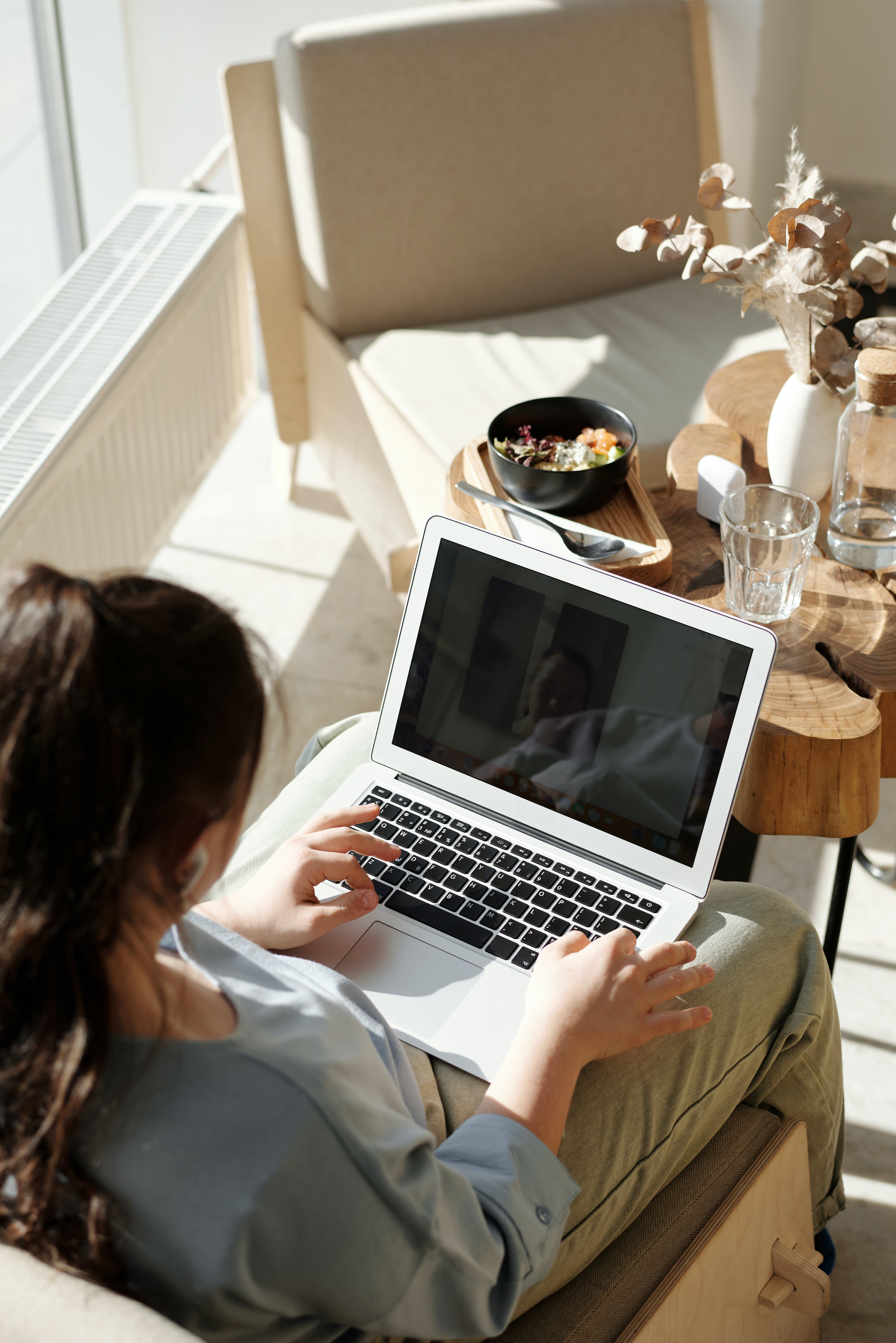 A focused woman on a couch, using a laptop for work.