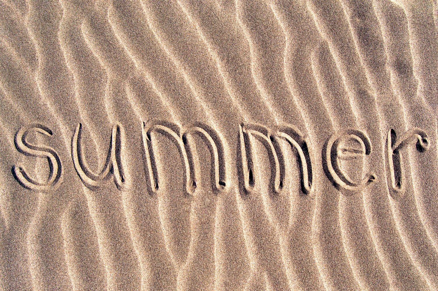 the word "summer" written in the sand