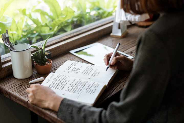 Individual writing in a journal, representing emotional self-care and clearing of negative memories. Individual writing in a journal, representing emotional self-care and clearing of negative memories.