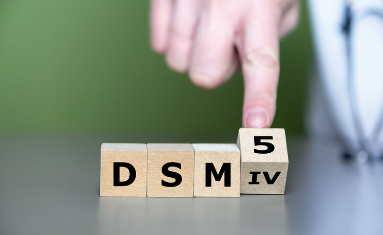 Stacked wooden blocks displaying DSM-IV and DSM-5, symbolizing the evolution of psychiatric diagnosis manuals listing 297 mental disorders with no biological testing methods. Stacked wooden blocks displaying DSM-IV and DSM-5, symbolizing the evolution of psychiatric diagnosis manuals listing 297 mental disorders with no biological testing methods.