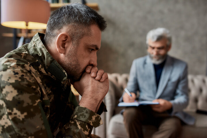 Distressed military veteran in therapy session, highlighting the emotional burden of trauma and the blurred line between PTSD diagnosis and natural post-traumatic stress. Distressed military veteran in therapy session, highlighting the emotional burden of trauma and the blurred line between PTSD diagnosis and natural post-traumatic stress.