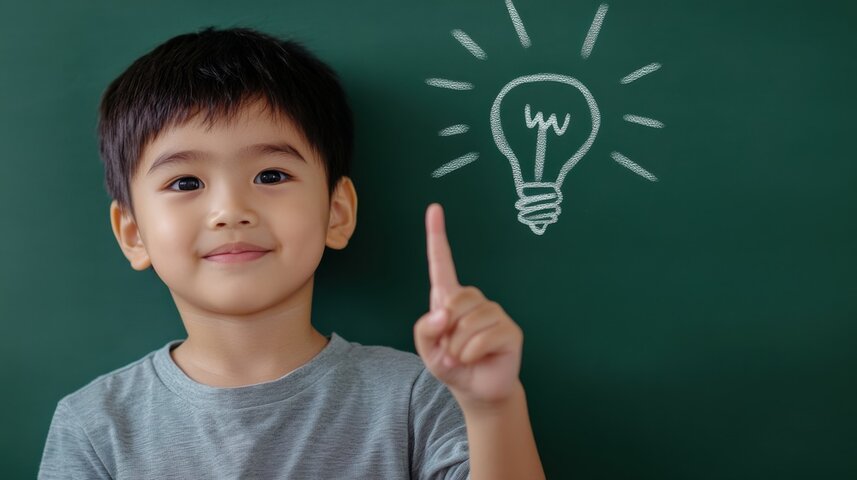 Smiling young boy pointing to a chalk-drawn lightbulb on a green chalkboard, representing hidden intelligence and the misunderstood potential behind severe autism labels. Smiling young boy pointing to a chalk-drawn lightbulb on a green chalkboard, representing hidden intelligence and the misunderstood potential behind severe autism labels.