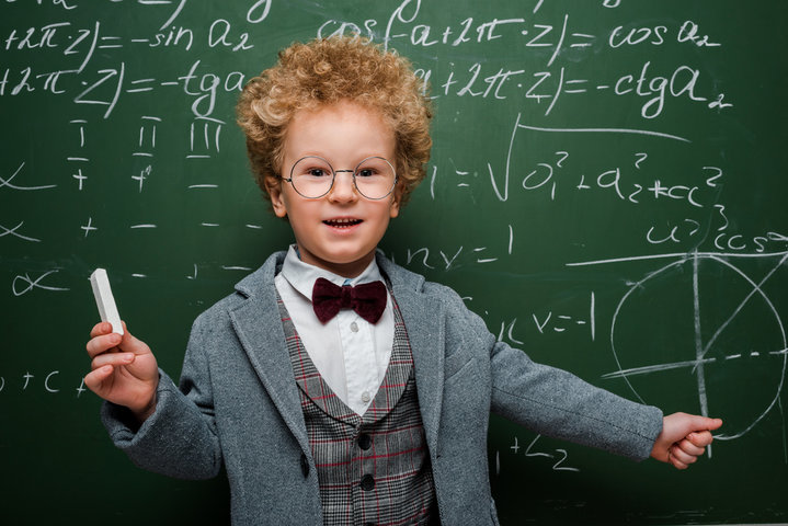 Young boy dressed as a professor in front of a chalkboard filled with equations, symbolizing the logic-based patterning behind autism behaviors from mild to severe expressions. Young boy dressed as a professor in front of a chalkboard filled with equations, symbolizing the logic-based patterning behind autism behaviors from mild to severe expressions.