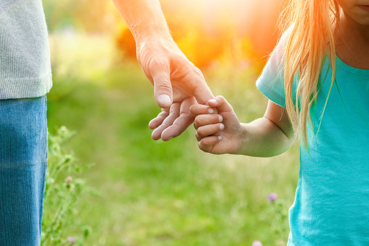 Adult gently holding a child's hand in a sunlit field, symbolizing safety, connection, and the quiet emergence of trust and presence in severe autism. Adult gently holding a child's hand in a sunlit field, symbolizing safety, connection, and the quiet emergence of trust and presence in severe autism.