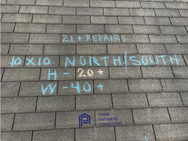 A section of a grey shingled roof marked with blue chalk during an inspection, indicating wind and hail damage. The markings read "10x10 NORTH/SOUTH," "H - 20+," and "W - 40+," along with "21+ REPAIRS," highlighting the areas affected by the damage. The logo "Prime Partners Consulting" is visible in the lower right corner. A section of a grey shingled roof marked with blue chalk during an inspection, indicating wind and hail damage. The markings read "10x10 NORTH/SOUTH," "H - 20+," and "W - 40+," along with "21+ REPAIRS," highlighting the areas affected by the damage. The logo "Prime Partners Consulting" is visible in the lower right corner.