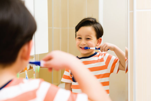 child brushing their teeth in front of a bathroom mirror child brushing their teeth in front of a bathroom mirror
