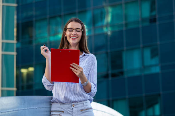 Insurance agent job seeker with clipboard and pen in front of office building