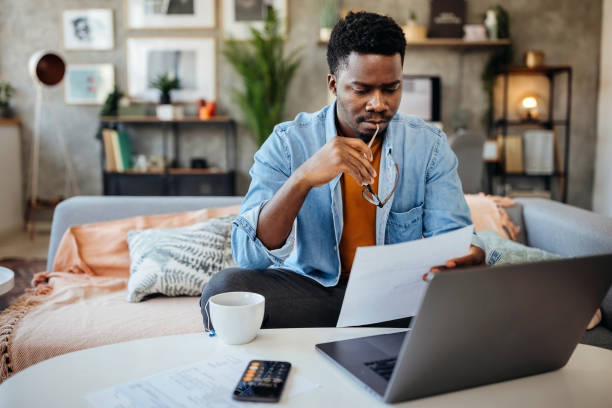 A photo of a person with a phone, calculator, and paperwork on a desk.