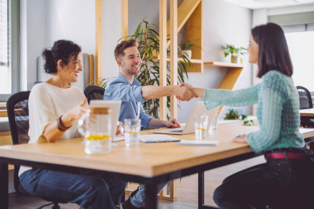An image showing a diverse group of people smiling and shaking hands on a business meeting or networking event.