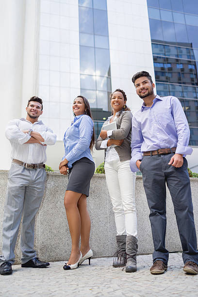 A diverse group of employees standing together in front of an office building to represent the positive and inclusive working environment at top insurance companies.