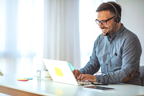 Insurance agent working remotely from a modern home office with a laptop, headset, and notepad. A comfortable and organized workspace with natural lighting and insurance-related elements in the background.