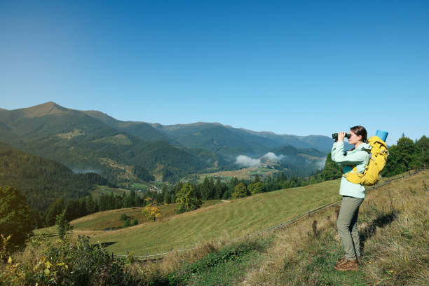 A person holding a pair of binoculars, looking out over a beautiful landscape.