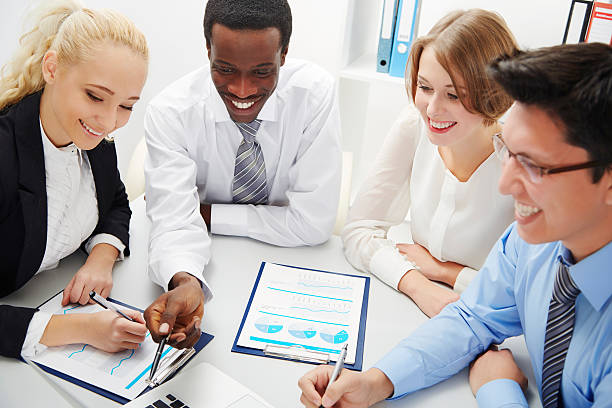 A diverse group of insurance agents discussing financial plans and showcasing their success with charts and graphs.