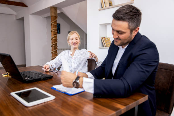 A young insurance agent demonstrating expertise and enthusiasm while interacting with clients, working at a modern desk with a laptop, and surrounded by charts and documents.