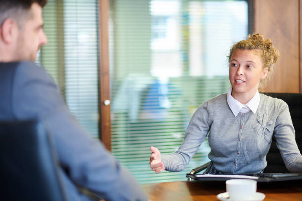 A person confidently sitting in a job interview setting, dressed in business attire and exhibiting a positive and professional demeanor.