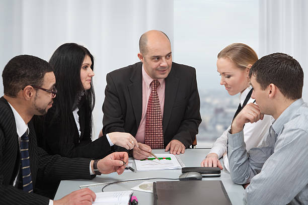 A group of insurance agents collaborating in a meeting, discussing data on a digital screen for building a solid portfolio in the insurance industry.