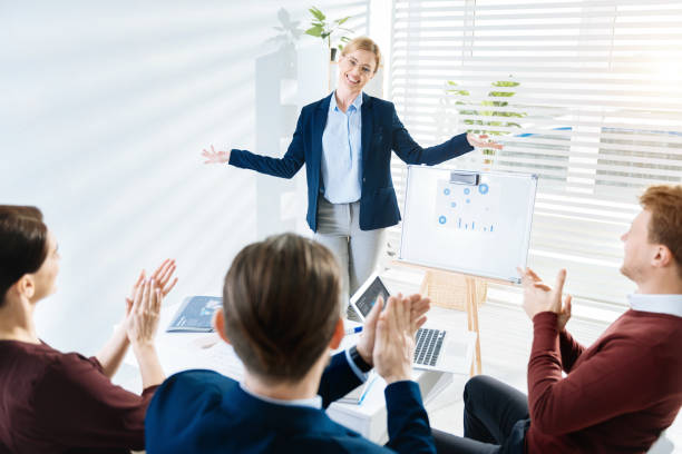 Excited female insurance agent presenting to a group of people, representing the potential for success and growth in the insurance industry.