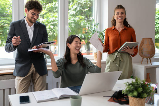 A diverse group of professionals in a modern office setting engaged in discussions and working on laptops.
