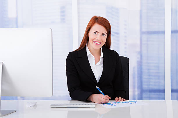 Entry level insurance agent sitting across from a happy-looking customer with a binder and pen in front of them.