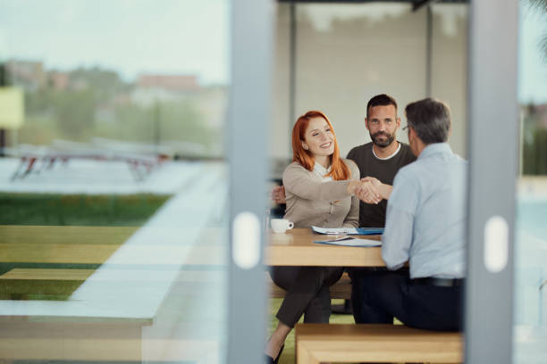Life insurance agent shaking hands with satisfied client after providing policy information.