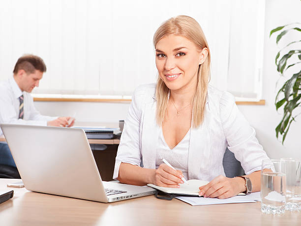 A health and life insurance agent, illustrating the art of balancing multiple policies, engaged with a client while sitting at a desk with policy documents and a laptop.